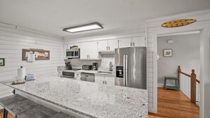 A modern kitchen with white cabinetry, stainless steel appliances, and a granite countertop.