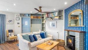 A cozy living room with a sofa, coffee table, and a fireplace. - A Coastal Haven at 2 Harbour View (Roundstone)