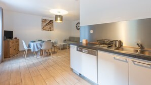 Una cocina moderna con lavavajillas, pileta y comedor con sillas y mesa.