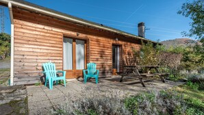 Una cabaña de madera con dos sillas y una mesa de picnic en el exterior.