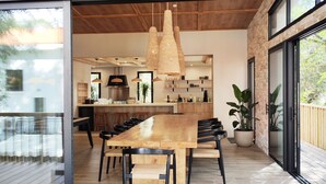 A modern kitchen with a large island, hanging light fixtures, and a view of the outdoors. - Villa Salicorne 210m2 with swimming pool (Saint-Brevin-les-Pins)