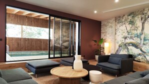A modern living room with a large sliding glass door leading to a pool area, a round wooden coffee table, and a large painting of a tree on the wall. - Villa Salicorne 210m2 with swimming pool (Saint-Brevin-les-Pins)
