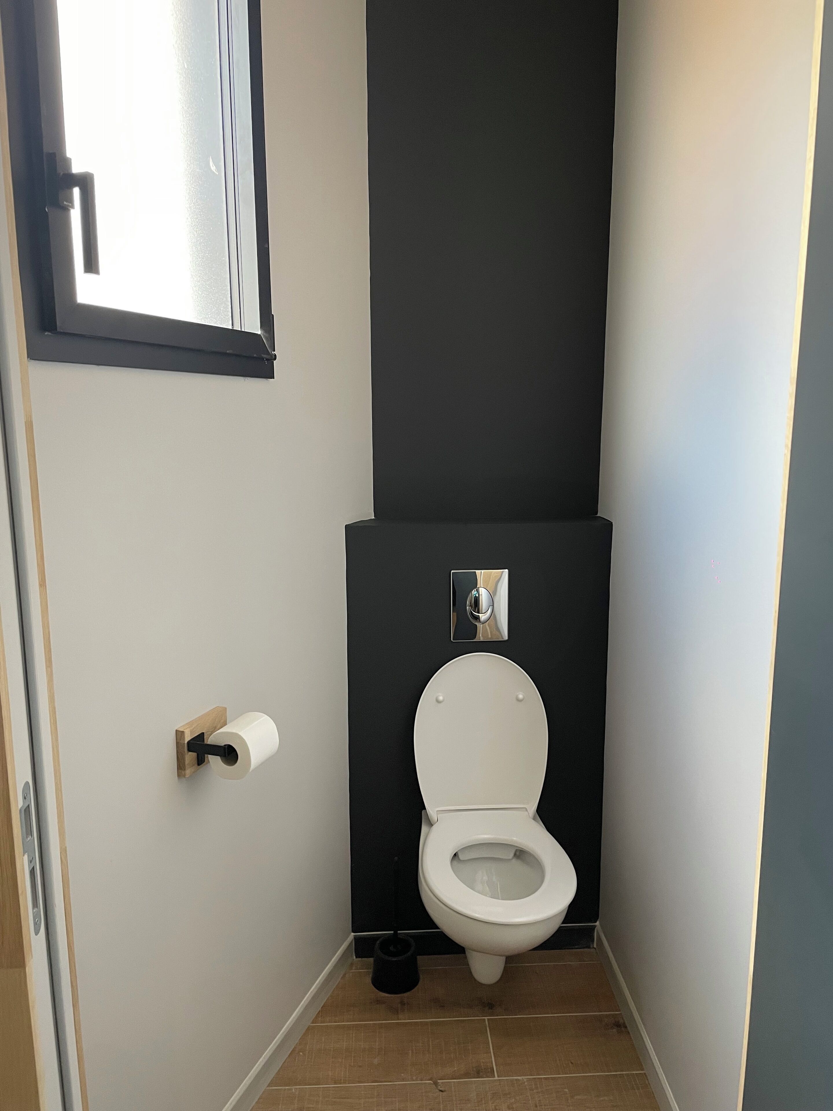 A small, modern bathroom with a toilet, a toilet paper holder, and a bidet.