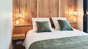 A bedroom with a wooden headboard, two bedside lamps, a bed with white bedding and green pillows, and a woven pendant light. - Villa Salicorne 210m2 with swimming pool (Saint-Brevin-les-Pins)
