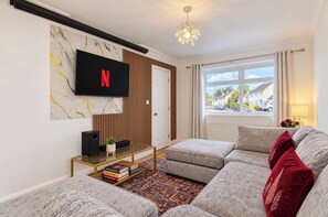 Un salon équipé d’un téléviseur à écran plat, d’un canapé, d’une table basse et d’un tapis à motifs.
