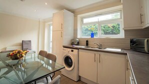 A compact kitchen with a washing machine, a toaster, and a window with a view of greenery. - Free parking | 7 beds | Contractor & Large groups (Berkshire)