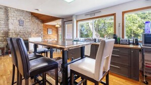 A modern kitchen with a stone wall, wooden ceiling, and large windows.