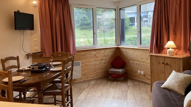 Une pièce chaleureuse avec une table et des chaises en bois, un canapé et un téléviseur fixé au mur.