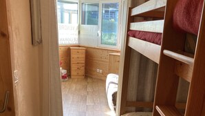 Une chambre avec un lit superposé, un plancher en bois, un bureau et une fenêtre donnant sur un paysage agréable.