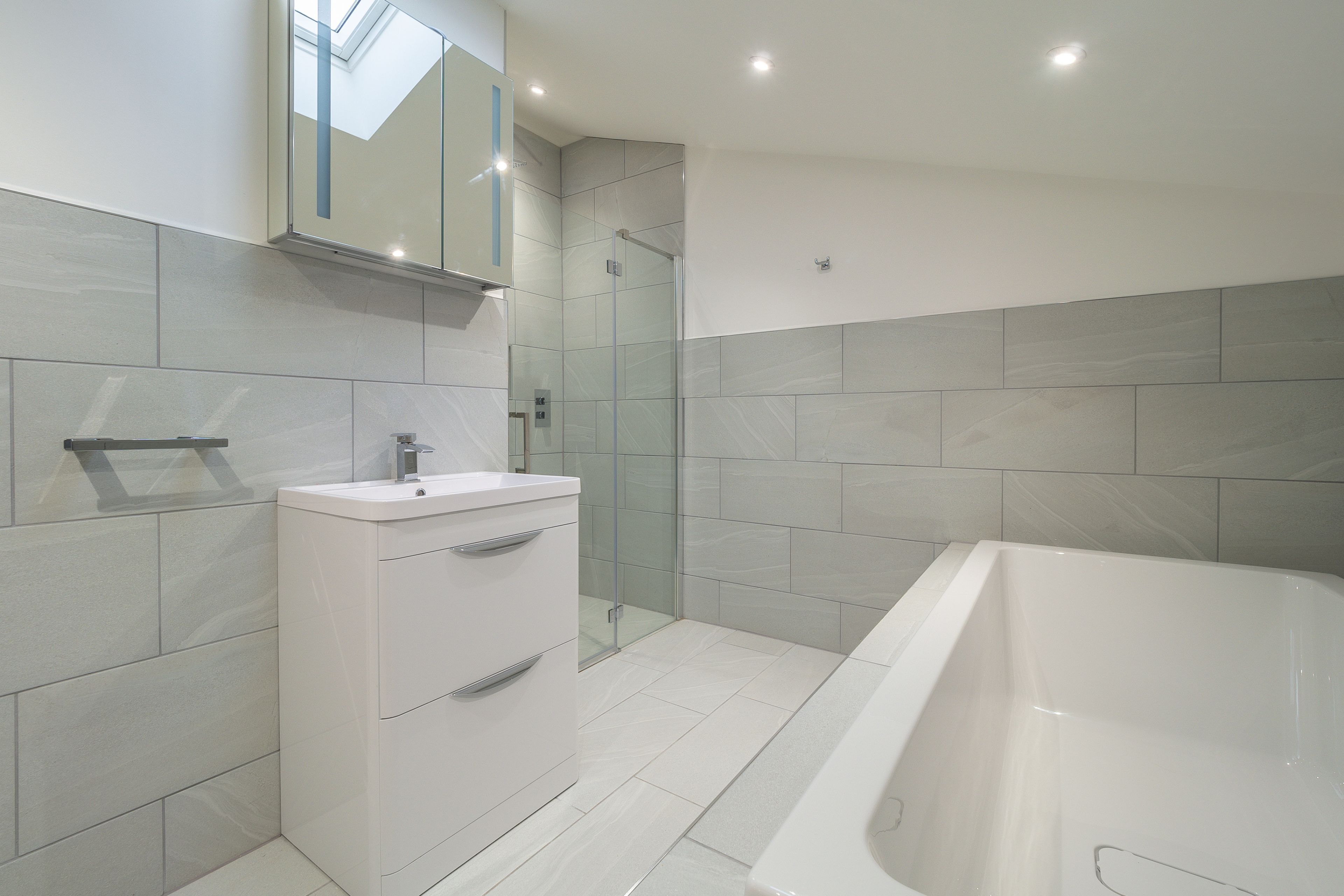 A modern bathroom with a glass-enclosed shower, a white vanity, and a freestanding bathtub.