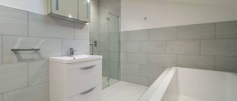 A modern bathroom with a glass-enclosed shower, a white vanity, and a freestanding bathtub.