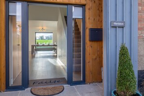 A modern building entrance with a wooden door, a sign reading "Mandalore", and a small potted plant.