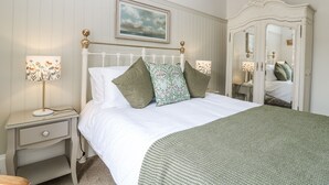 A neatly made bed with a white headboard, two bedside lamps, and a green throw blanket.