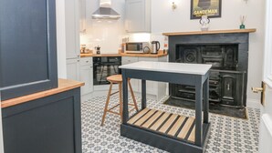 A modern kitchen with white cabinets, a black stove, and a tiled floor.