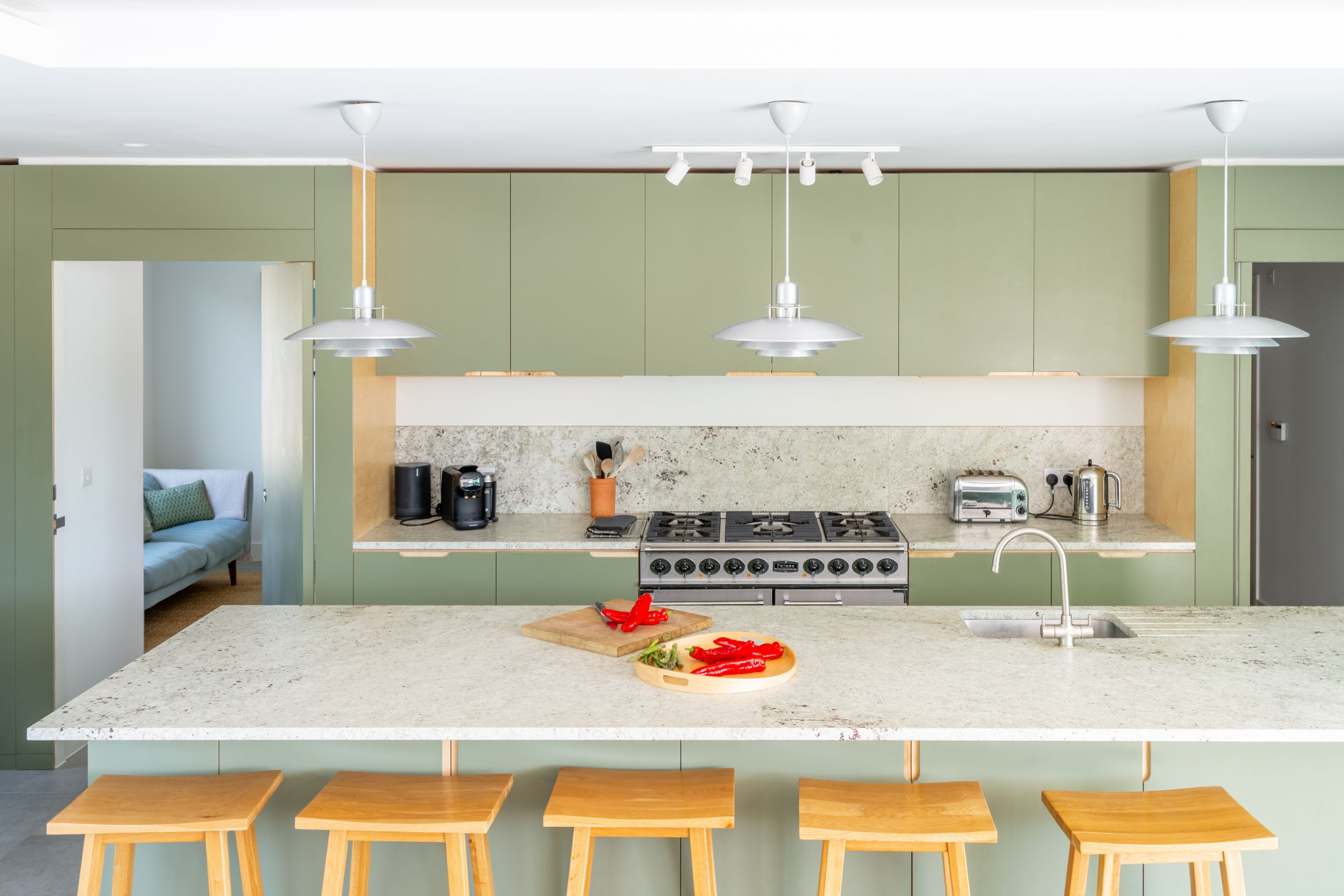 A modern kitchen with a central island, bar stools, a gas stove, and pendant lighting.
