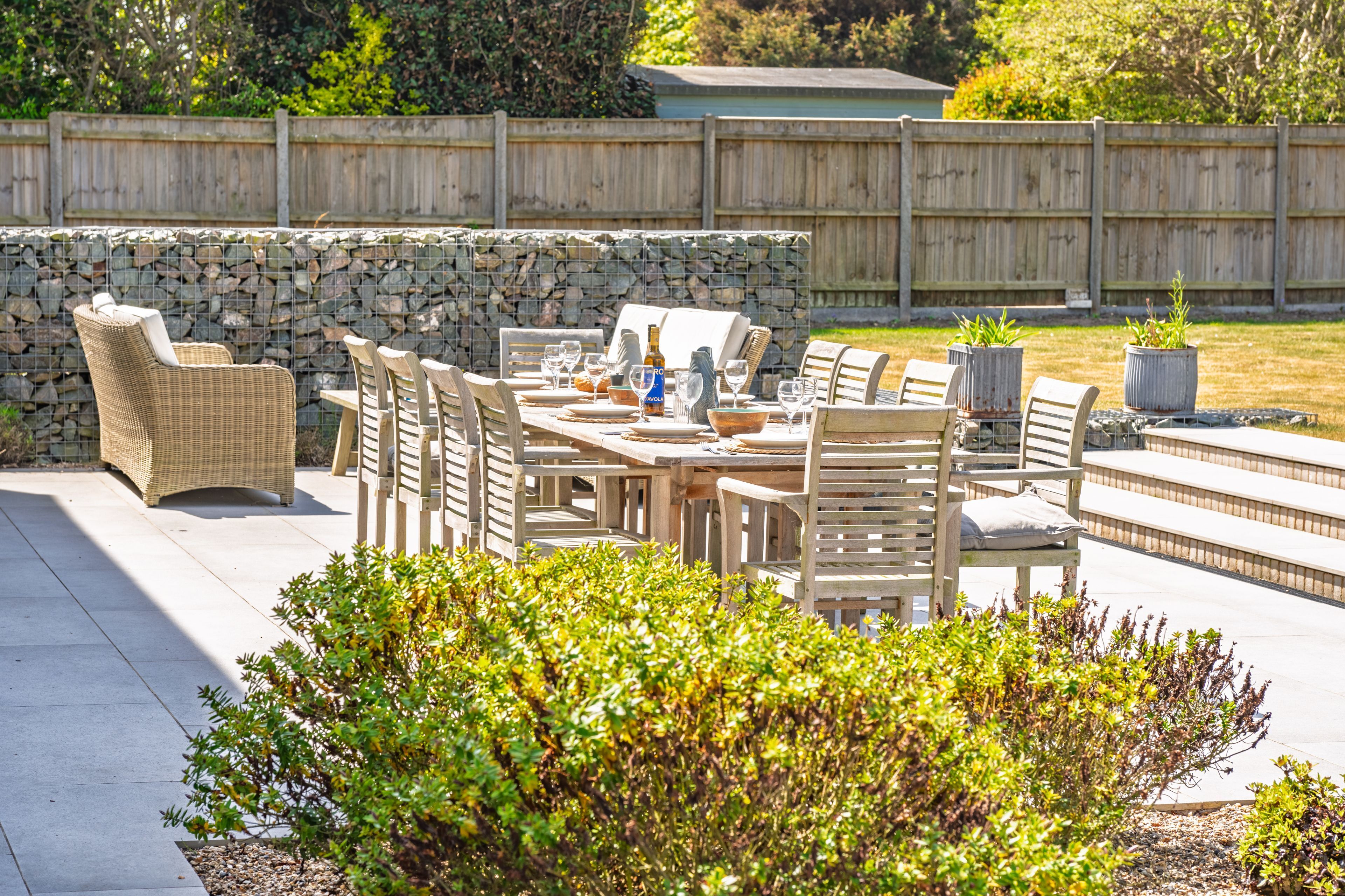 An outdoor patio with a stone wall, wicker furniture, and a grill.