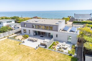 Une maison moderne à deux étages, dotée d’une grande terrasse, d’une piscine et offrant une vue sur l’océan.