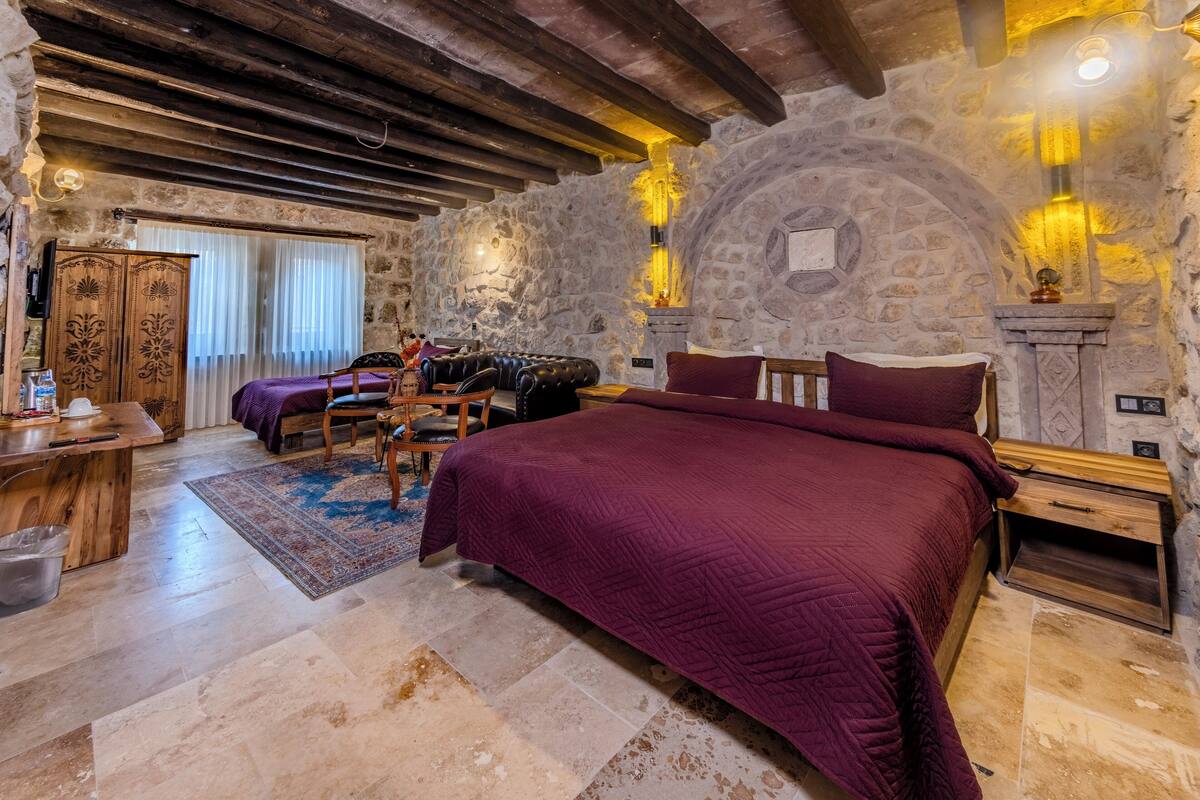 Ein Schlafzimmer mit einem großen Bett, einem Holztisch, einer Steinwand und einem Kamin aus Stein.
