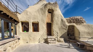 A building with a unique, textured exterior and a stone staircase leading to a wooden door. - Rose Moon Cave (Nevşehir)