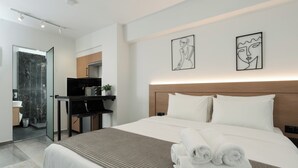 A modern hotel room with a large bed, a desk, and a bathroom. - TOWER 15 Suites (Thessaloniki)
