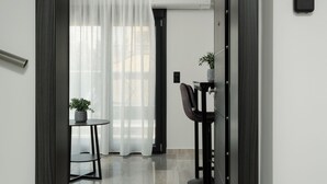 A modern hotel entrance with a dark wooden door, a number sign '501', a small table with a plant, and a chair. - TOWER 15 Suites (Thessaloniki)