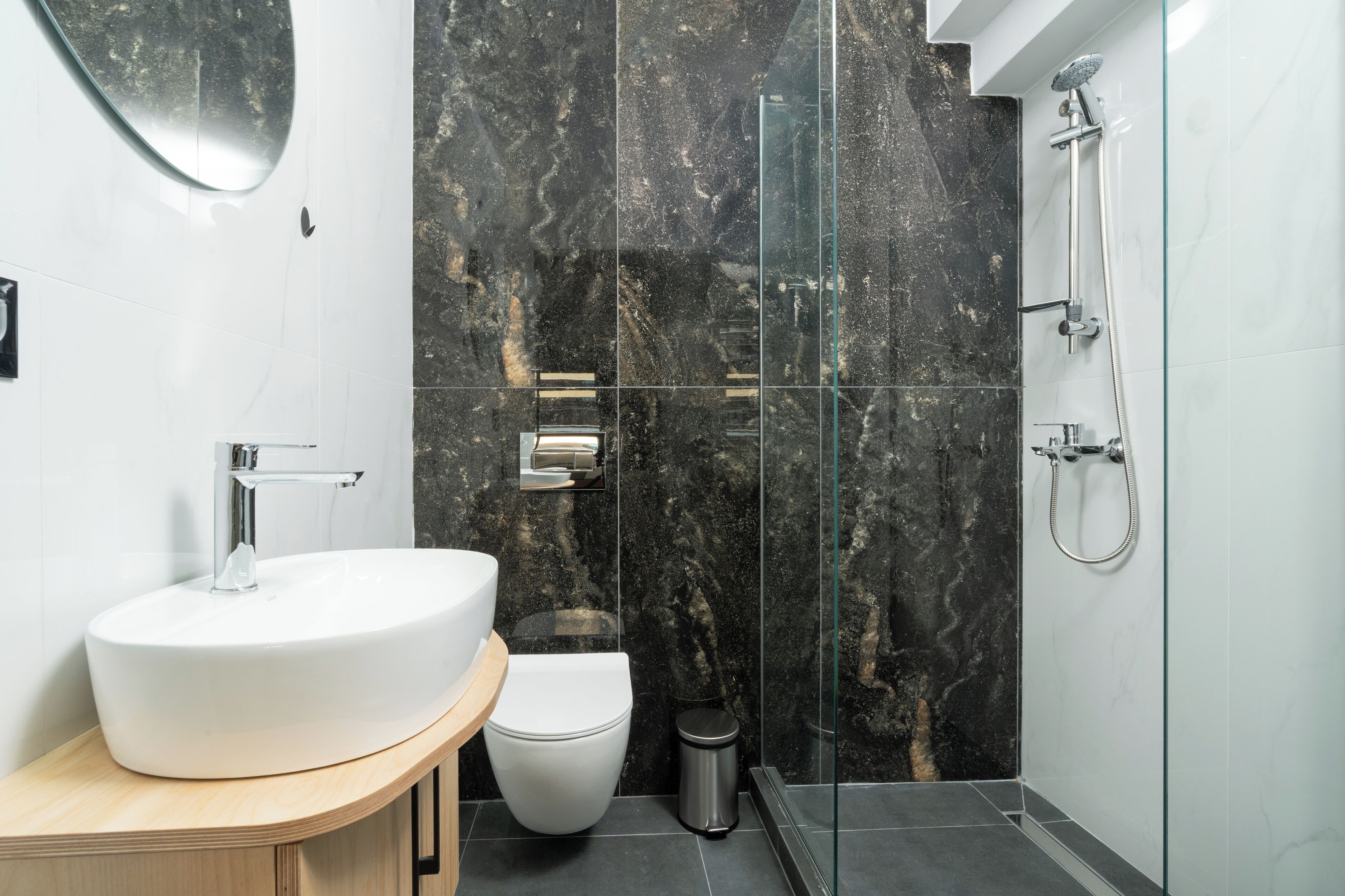 Een moderne badkamer met een witte wastafel, toilet en een douchecabine met glazen wanden.