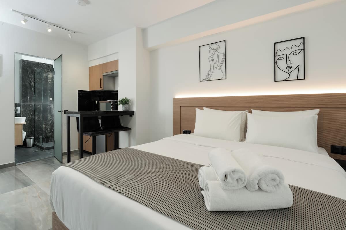 A modern hotel room with a large bed, a desk, and a bathroom.