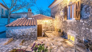 A stone building with a tiled roof, a wooden door, and a small window with shutters.