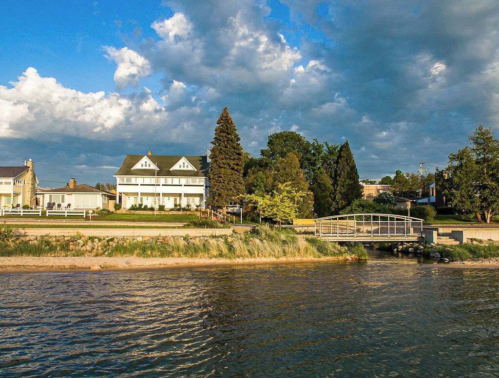 A riverside view with a bridge, a large white building with a green roof, and surrounding greenery.