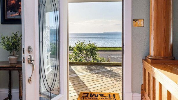 Eine offene Tür, die zu einem Balkon mit Meerblick führt.
