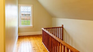 A narrow stairway with wooden railings leading to a landing. - Historic PEI Cottage with Modern Comforts, Riverside Views & Family-Friendly Fun (Prince Edward Island)