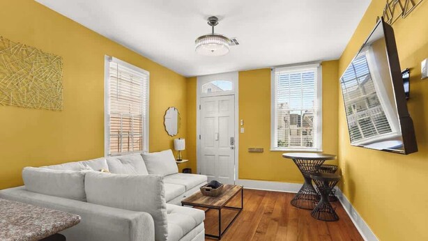 A living room with a sofa, coffee table, and a dining area with a small table and chairs. - Beautiful Bywater Retreat with Private Patio (New Orleans)