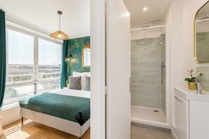 A modern bedroom with a large bed, a shower, and a view of the city. - Family Suite - Finlay (Paris)