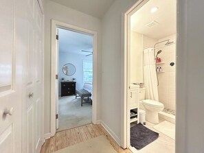 Corridoio che conduce a un bagno con doccia, WC e un piccolo sedile.