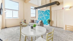 A modern interior with a round table, chairs, a sofa, and a geometric wall design. - Downtown · Gym · Sauna · Parking · Pet Friendly (Cleveland)