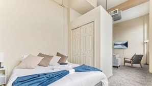 A hotel room with a bed, a chair, a TV, and a door. - Downtown · Gym · Sauna · Parking · Pet Friendly (Cleveland)