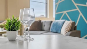 A modern living room with a marble table, two clear wine glasses, a small potted plant, and a geometric wall design. - Downtown · Gym · Sauna · Parking · Pet Friendly (Cleveland)