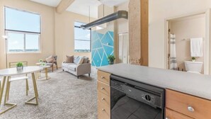 A modern kitchen with a dishwasher, a dining area with a table and chairs, and a living room with a sofa and a coffee table. - Downtown · Gym · Sauna · Parking · Pet Friendly (Cleveland)