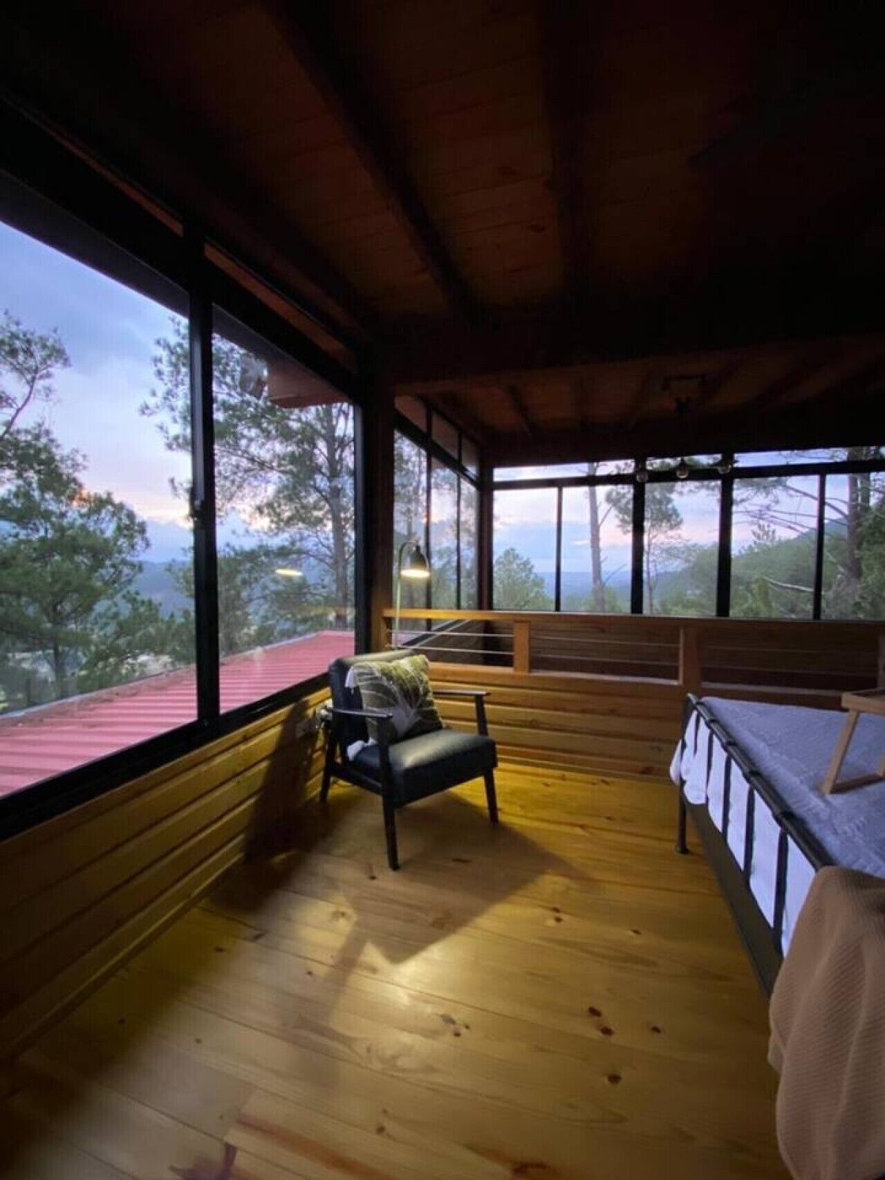 Une cabane avec une terrasse en bois, un banc et un lit.