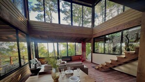A modern interior with a wooden dining table, seating, and a staircase leading to an upper level.