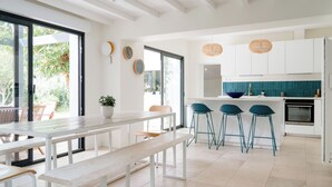 A modern kitchen with white cabinetry, a central island with stools, and a large window providing natural light.