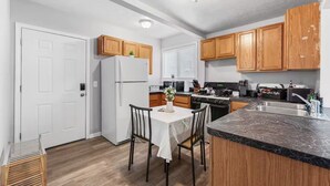 A modern kitchen with wooden cabinets, a white refrigerator, a dining table with chairs, and a built-in oven.