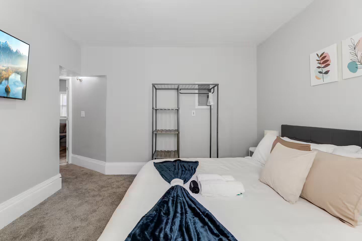 Una habitación de hotel con una cama, un armario, una estantería y un cuadro en la pared.