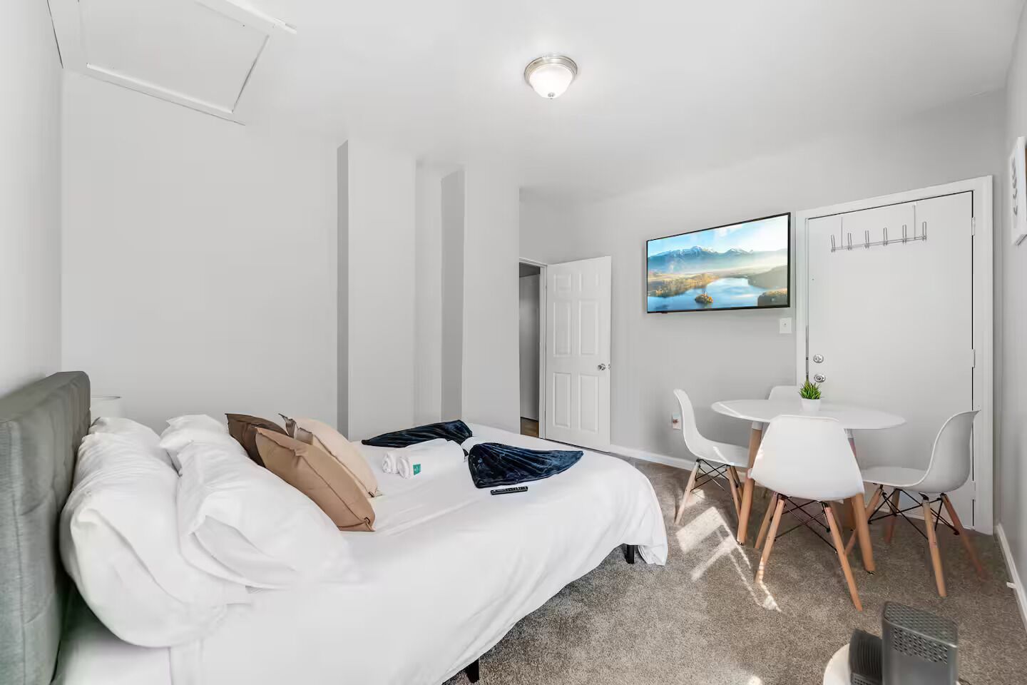Une chambre d’hôtel avec un lit, une petite table avec des chaises, une télévision et une porte.