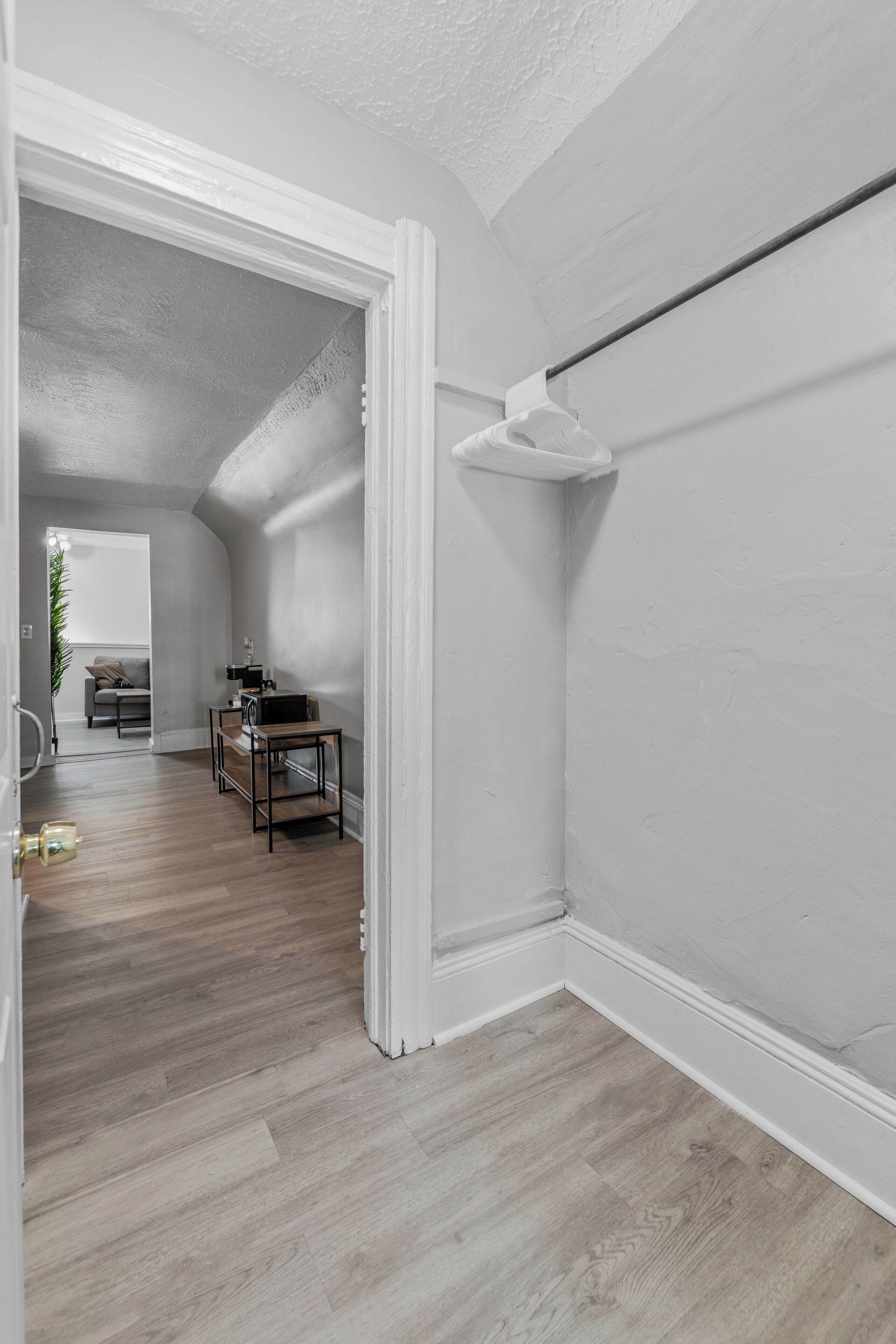 A hallway with a wooden floor, white walls, and a ceiling fan.