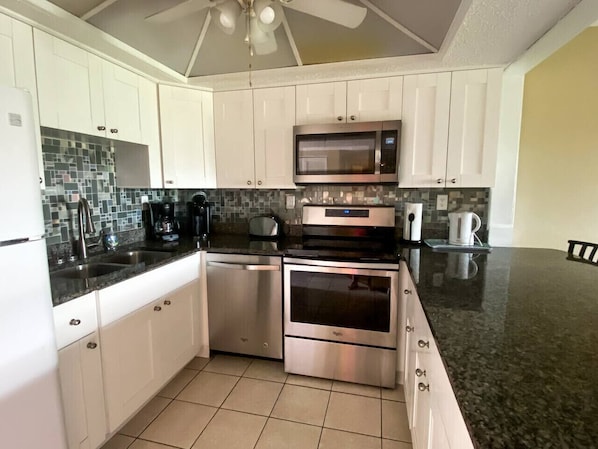 A modern kitchen with white cabinets, stainless steel appliances, a microwave, oven, and a dishwasher.