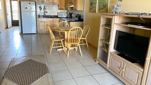 Une cuisine dotée de meubles en bois, d’un réfrigérateur, d’un four à micro-ondes et d’un coin repas avec une table et des chaises.
