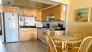 Une cuisine dotée de meubles en bois, d’un réfrigérateur, d’un four à micro-ondes, d’une cuisinière et d’une table à manger avec des chaises.