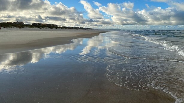 Une plage avec un large rivage sablonneux et des vagues douces.