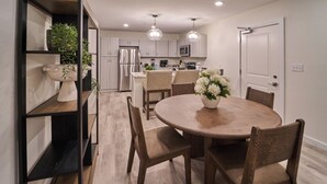 Une cuisine moderne avec des meubles blancs, un îlot central et des luminaires suspendus.